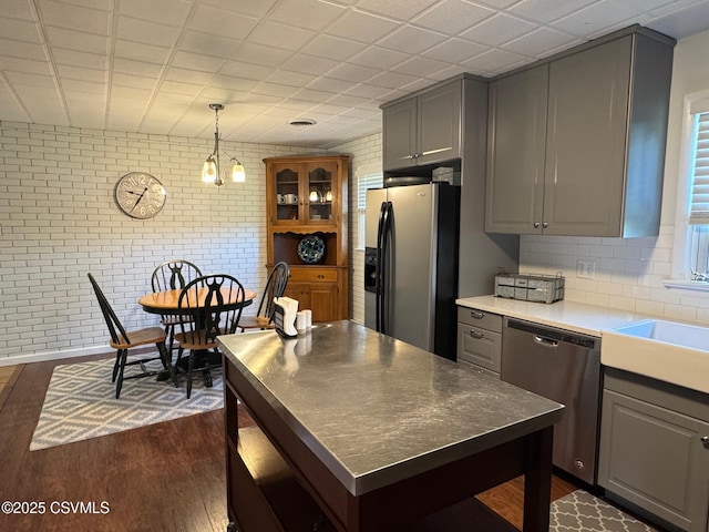 150 Blue Spruce Ln, Shamokin, PA 17872 - kitchen with refrigerator with ice dispenser, stainless steel dishwasher, gray cabinets, dark wood finished floors, and brick wall
