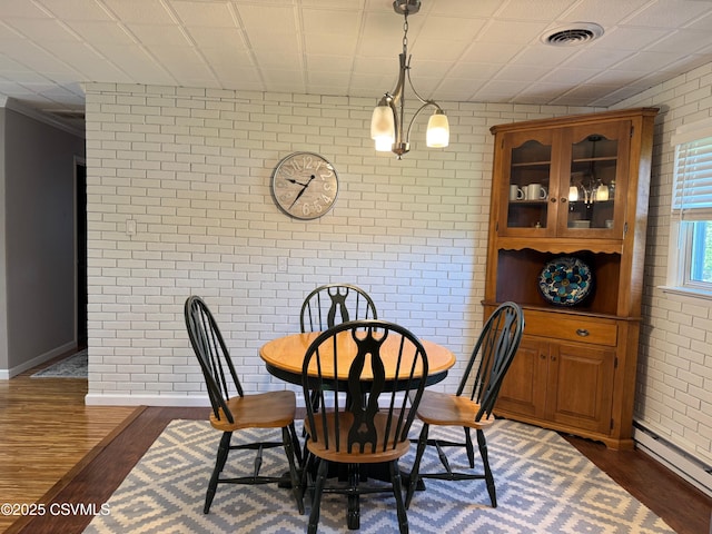 150 Blue Spruce Ln, Shamokin, PA 17872 - dining space featuring brick wall, a baseboard radiator, and dark wood finished floors