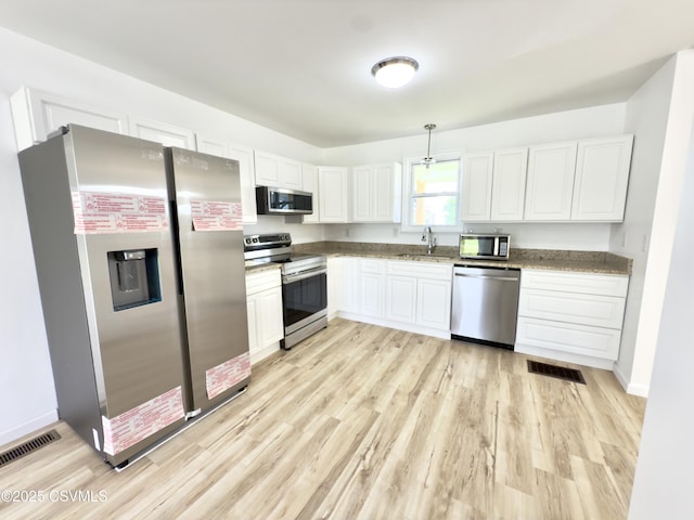 1613 2nd Ave, Berwick, PA 18603 - kitchen with stainless steel appliances, white cabinetry, light wood finished floors, and decorative light fixtures