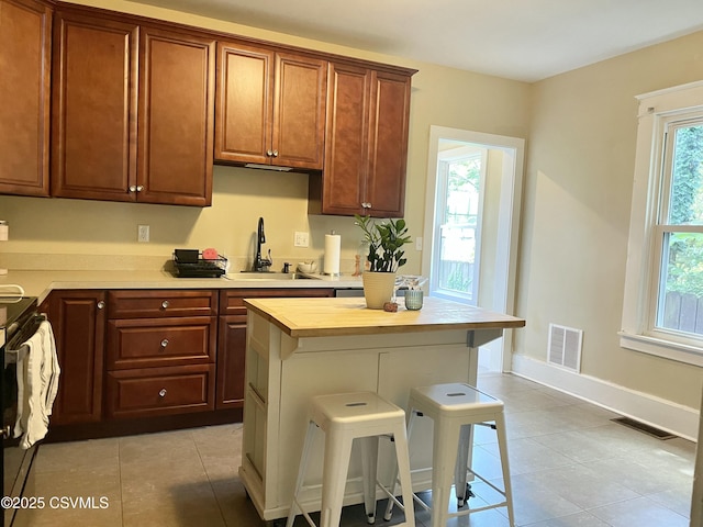 130-132 S 5th St, Lewisburg, PA 17837 - kitchen with light tile patterned floors, a breakfast bar, electric range, butcher block countertops, and a kitchen island