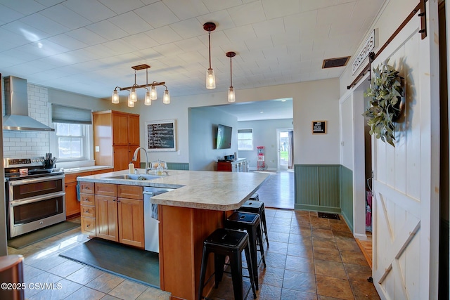 4429 Rte 204, Selinsgrove, PA 17870 - kitchen featuring stainless steel appliances, wall chimney exhaust hood, light countertops, open floor plan, and wainscoting
