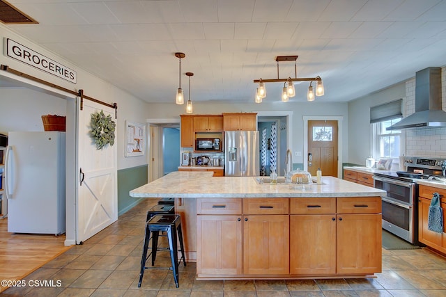 4429 Rte 204, Selinsgrove, PA 17870 - kitchen with appliances with stainless steel finishes, wall chimney range hood, a barn door, an island with sink, and decorative light fixtures