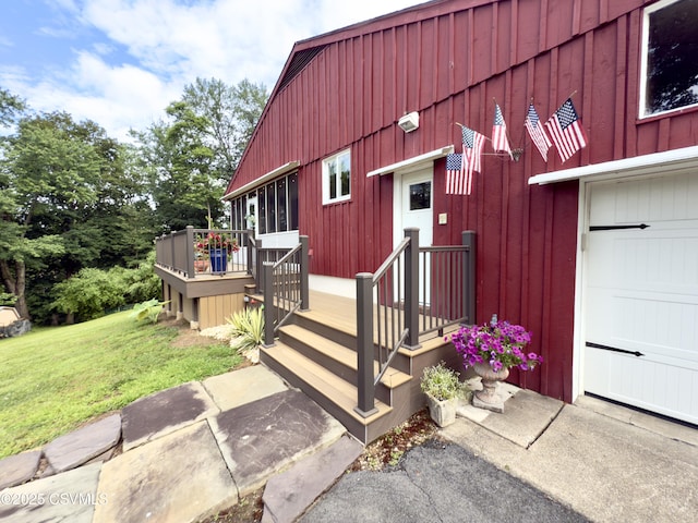 101 Twig Ln, Sunbury, PA 17801 - view of exterior entry featuring a yard, a garage, a wooden deck, and board and batten siding