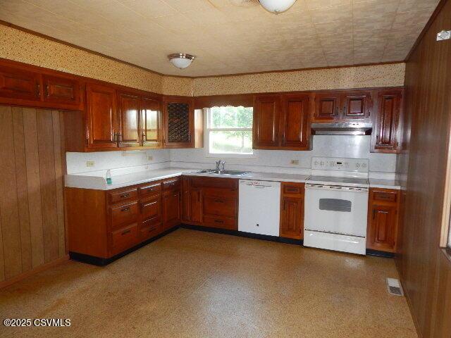 404 W Center St, Elysburg, PA 17824 - kitchen featuring white appliances, under cabinet range hood, light countertops, wood walls, and brown cabinetry