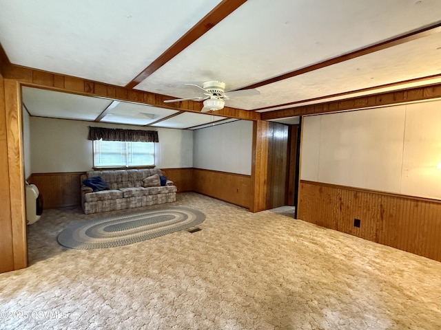25 Wolfe Rd, Nescopeck, PA 18635 - carpeted living room featuring wainscoting, wood walls, beam ceiling, and ceiling fan