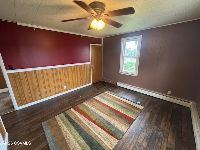1715 Spring Garden Ave, Berwick, PA 18603 - spare room with baseboard heating, hardwood / wood-style flooring, a ceiling fan, wooden walls, and ornamental molding