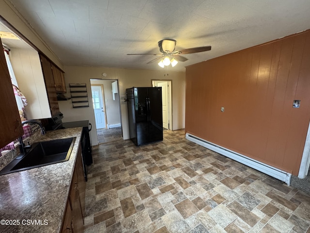 1715 Spring Garden Ave, Berwick, PA 18603 - kitchen featuring black fridge, baseboard heating, a ceiling fan, stone finish floors, and wooden walls