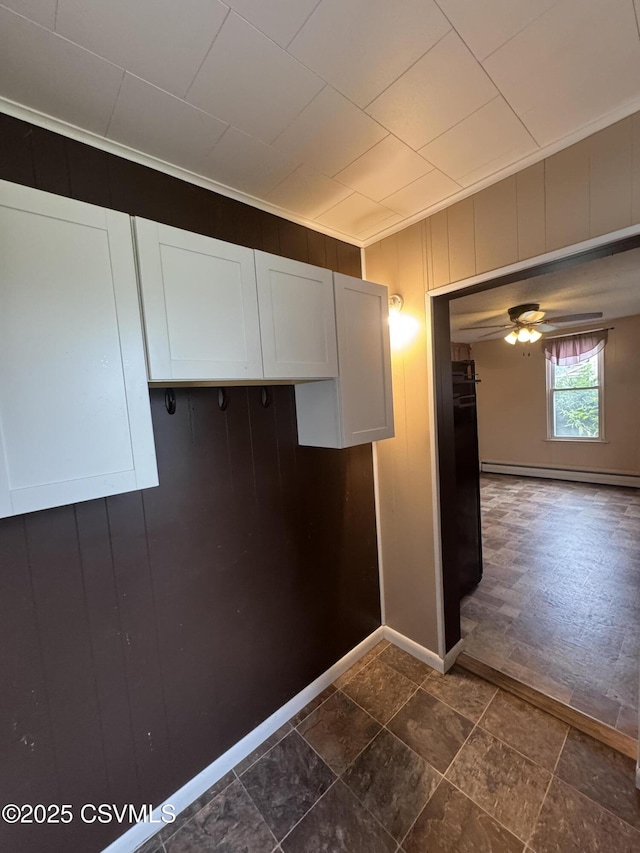 1715 Spring Garden Ave, Berwick, PA 18603 - kitchen featuring baseboard heating, white cabinets, a ceiling fan, wooden walls, and crown molding