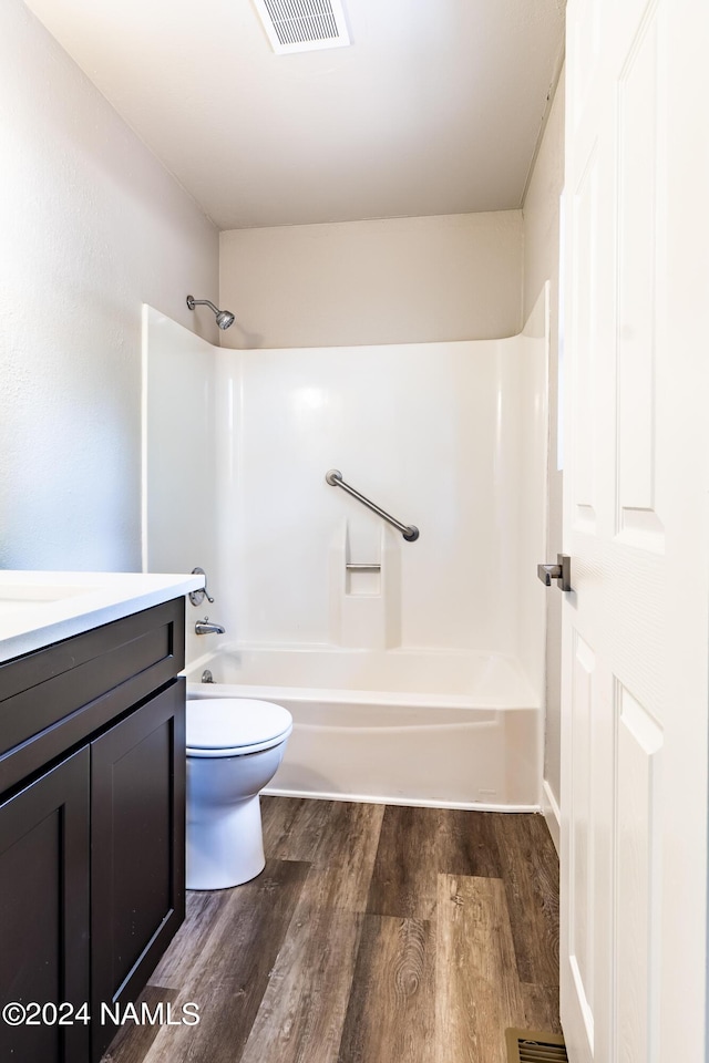 full bathroom with hardwood / wood-style floors, toilet, shower / tub combination, and vanity