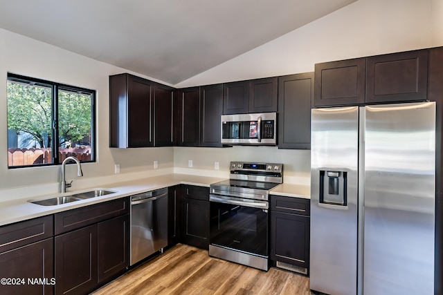 kitchen with sink, appliances with stainless steel finishes, light hardwood / wood-style flooring, and vaulted ceiling