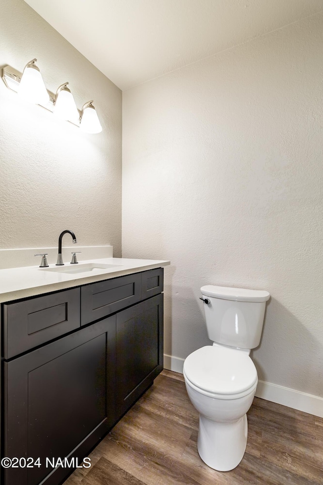 bathroom with hardwood / wood-style flooring, toilet, and vanity