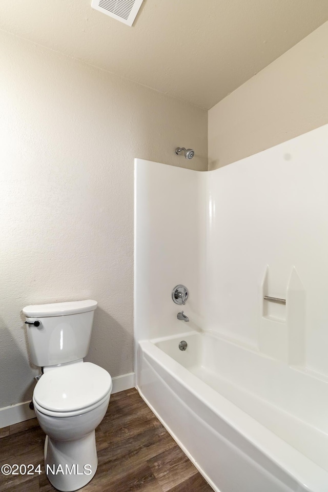 bathroom with shower / bathtub combination, wood-type flooring, and toilet