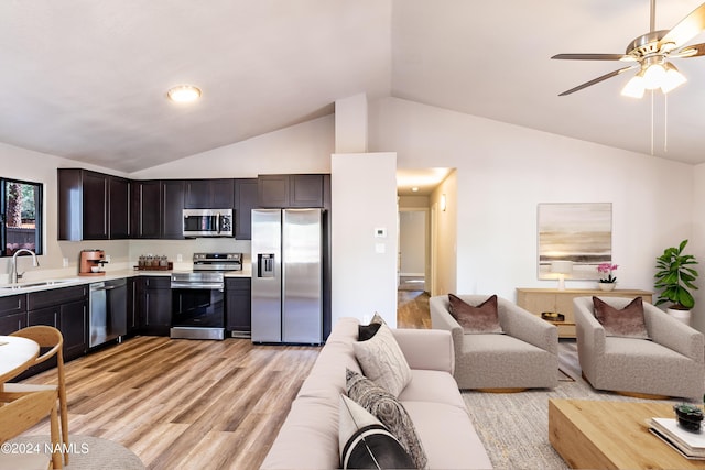 kitchen with dark brown cabinets, light hardwood / wood-style flooring, appliances with stainless steel finishes, sink, and lofted ceiling