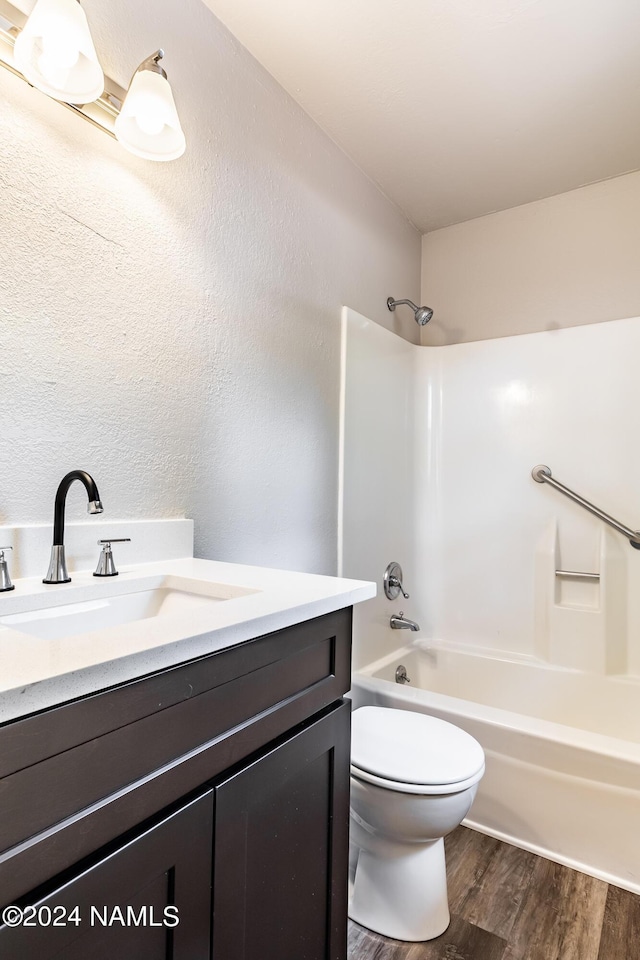 full bathroom featuring hardwood / wood-style flooring, toilet, bathtub / shower combination, and vanity