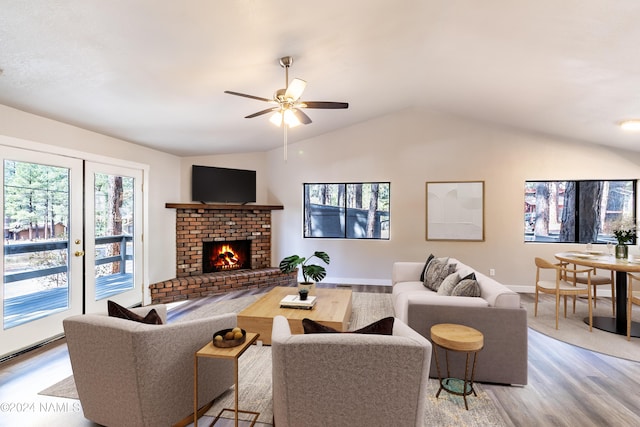 living room featuring a brick fireplace, light hardwood / wood-style flooring, ceiling fan, and vaulted ceiling