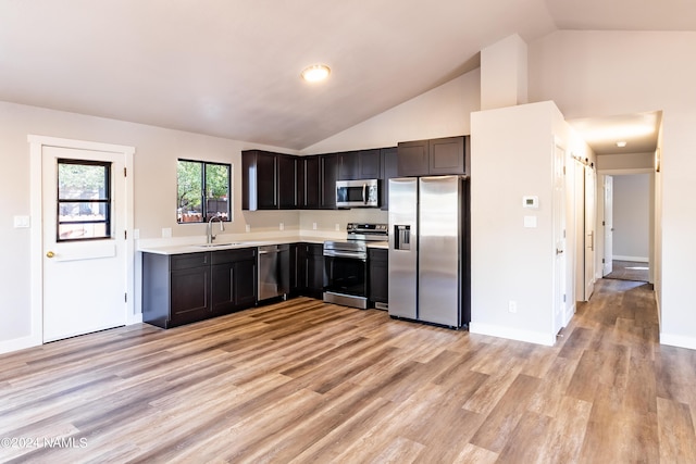 kitchen featuring light hardwood / wood-style floors, vaulted ceiling, sink, dark brown cabinets, and stainless steel appliances