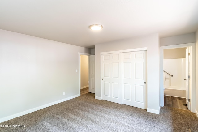 unfurnished bedroom featuring a closet, carpet floors, and ensuite bath