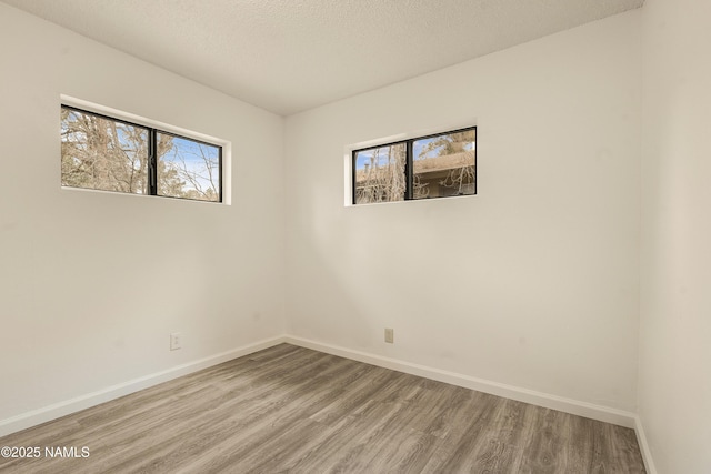 empty room with wood-type flooring and a textured ceiling