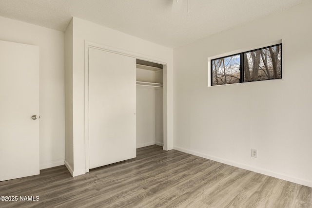 unfurnished bedroom featuring wood-type flooring, a textured ceiling, and a closet