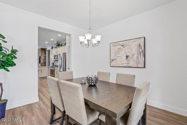 dining area featuring wood-type flooring and an inviting chandelier