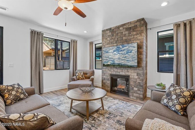 living room featuring ceiling fan, a brick fireplace, and light hardwood / wood-style flooring