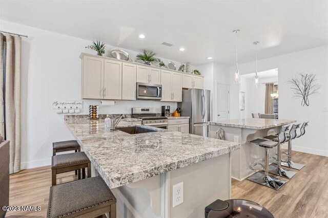 kitchen with a kitchen bar, appliances with stainless steel finishes, white cabinets, kitchen peninsula, and pendant lighting