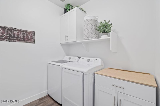 clothes washing area featuring cabinets, dark hardwood / wood-style floors, and washing machine and clothes dryer