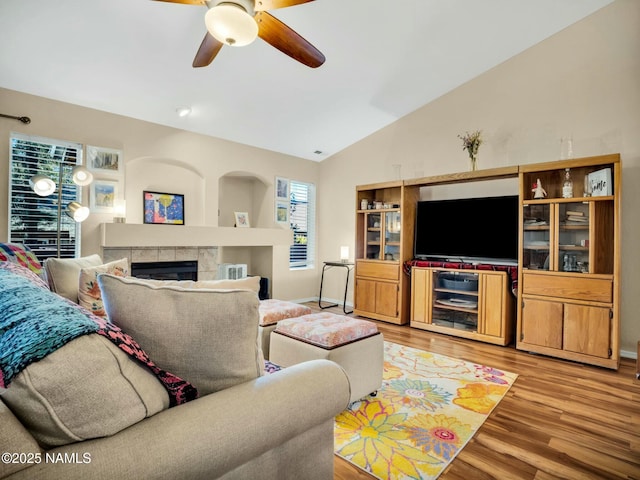 living room with vaulted ceiling, ceiling fan, a fireplace, and light hardwood / wood-style flooring