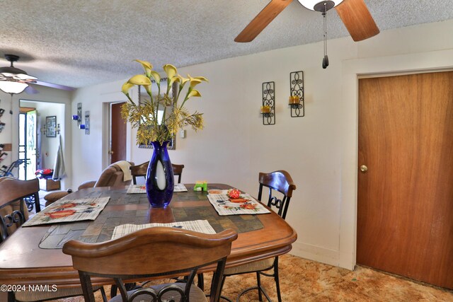 dining space with ceiling fan, light colored carpet, and a textured ceiling