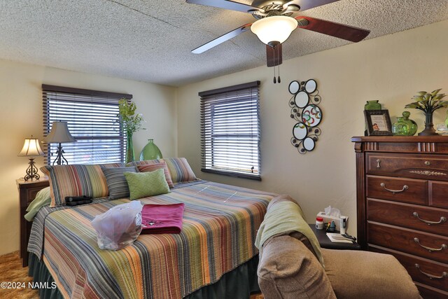 bedroom featuring multiple windows, a textured ceiling, and ceiling fan