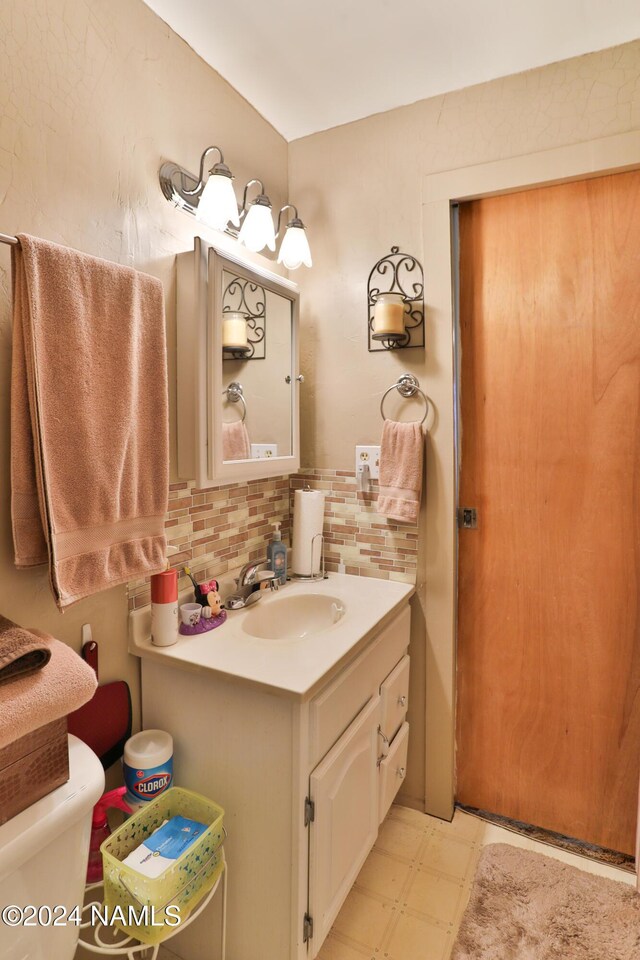 bathroom with vanity, backsplash, and toilet