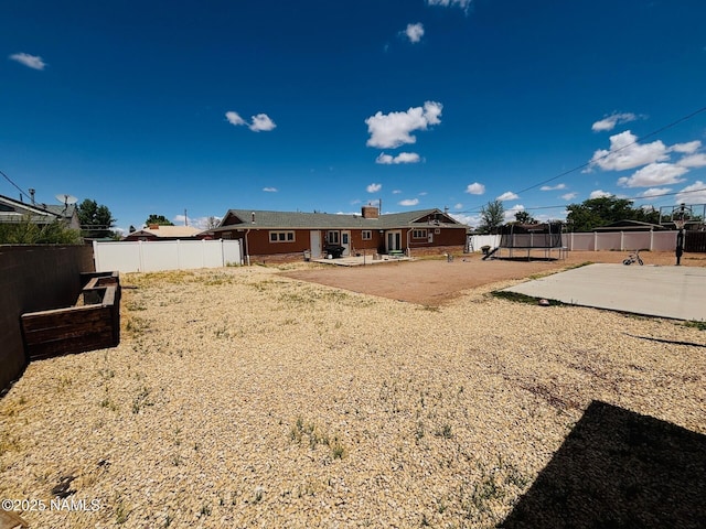 back of property with a trampoline, a patio area, and a fenced backyard