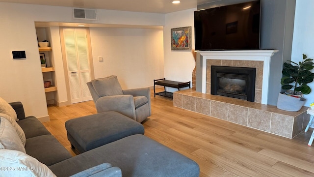 living area with wood finished floors, recessed lighting, and a tiled fireplace