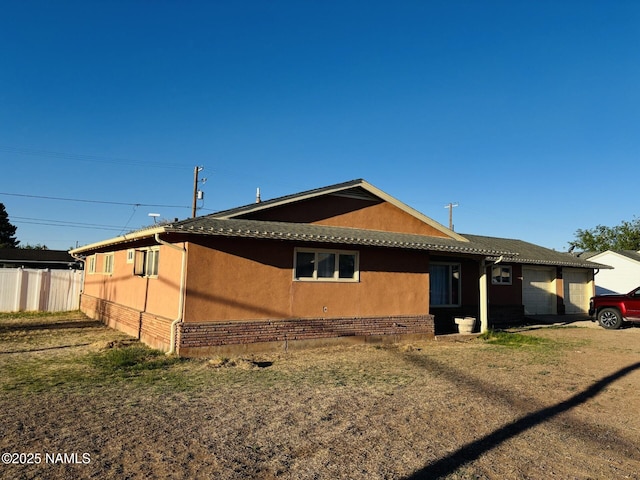 view of home's exterior featuring fence, brick siding, and stucco siding
