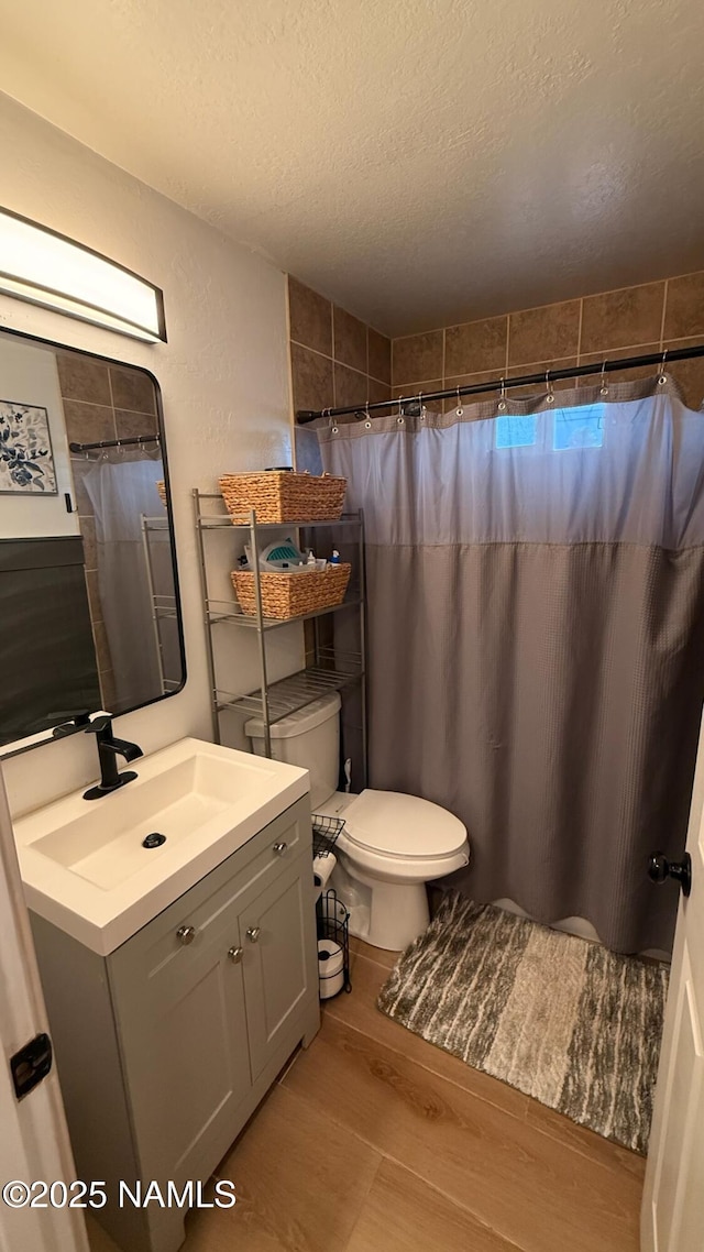 bathroom with a textured ceiling, wood finished floors, vanity, toilet, and a shower with shower curtain