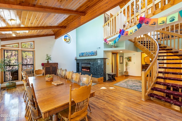 dining space with a fireplace, wooden ceiling, hardwood / wood-style floors, and vaulted ceiling with beams