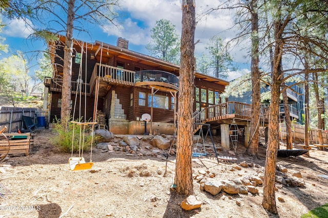 rear view of property featuring a balcony and a wooden deck