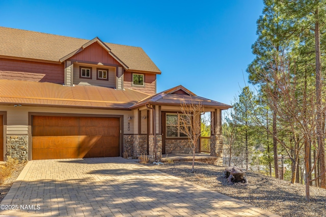 rustic home with stone siding, decorative driveway, an attached garage, and board and batten siding