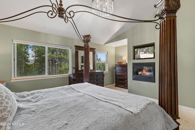 carpeted bedroom with an inviting chandelier and vaulted ceiling