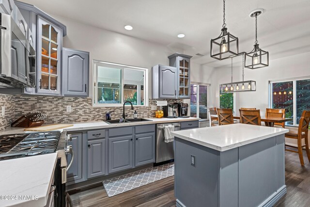 kitchen featuring appliances with stainless steel finishes, a center island, sink, hanging light fixtures, and gray cabinets