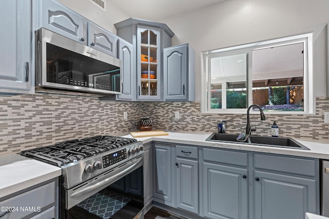 kitchen with sink, gray cabinets, decorative backsplash, and appliances with stainless steel finishes