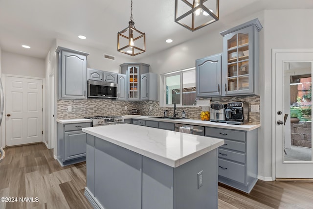 kitchen featuring pendant lighting, a center island, stainless steel appliances, and gray cabinetry