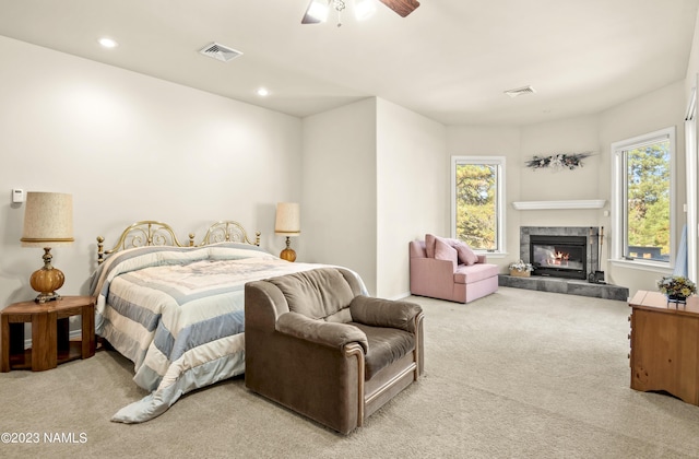 bedroom featuring ceiling fan, light colored carpet, and a fireplace