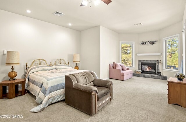 bedroom featuring ceiling fan, light colored carpet, and a fireplace