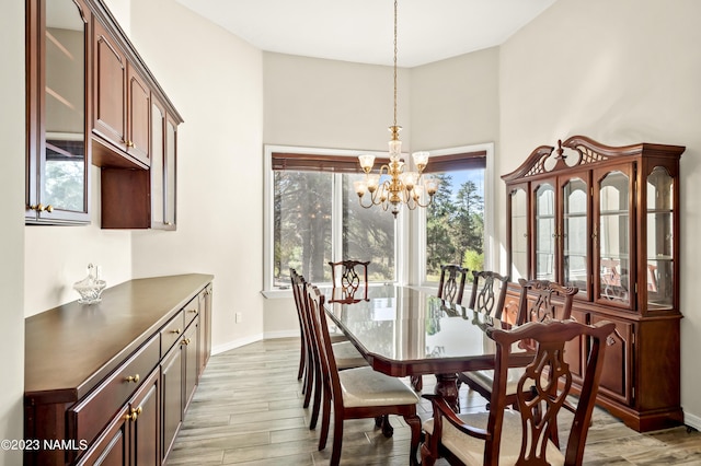 dining space with light hardwood / wood-style floors and a notable chandelier