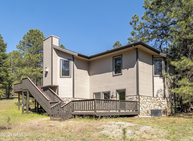 rear view of property featuring a yard, cooling unit, and a deck