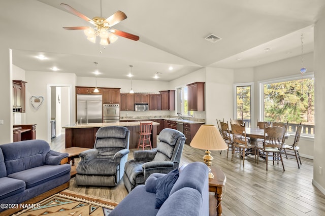 living room with ceiling fan, sink, vaulted ceiling, and light wood-type flooring