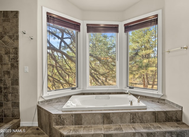 bathroom featuring a relaxing tiled tub and a wealth of natural light