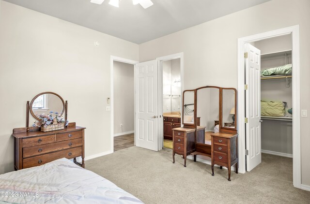 carpeted bedroom featuring a walk in closet, ceiling fan, connected bathroom, and a closet