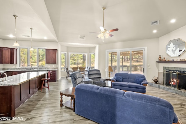 living room with sink, ceiling fan, light hardwood / wood-style floors, and a fireplace